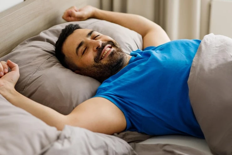 happy-middle-eastern-man-stretching-bed-after-good